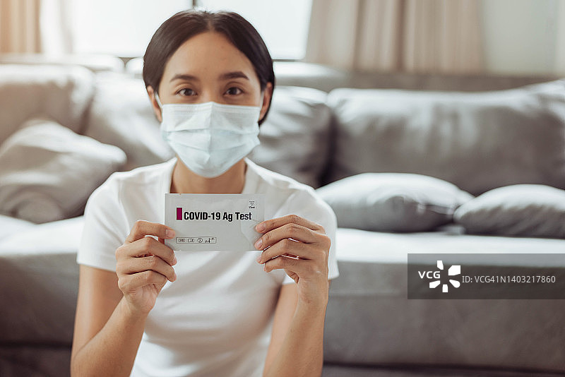 年轻女子在家使用抗原试剂盒进行新冠病毒自测图片素材