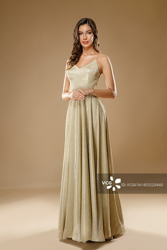 身穿香槟色无袖长裙的年轻时装模特看着镜头图片素材