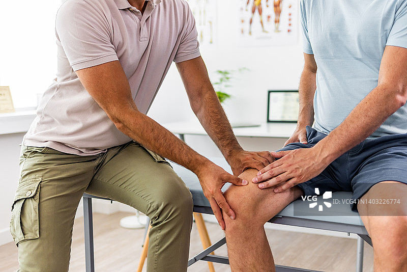 理疗师治疗男性运动员的膝盖损伤图片素材