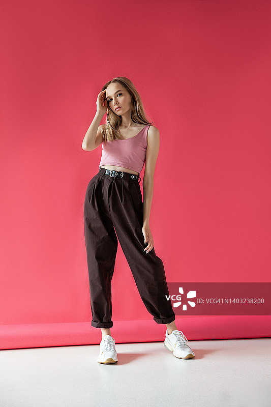 触摸粉色背景的时尚年轻女性图片素材