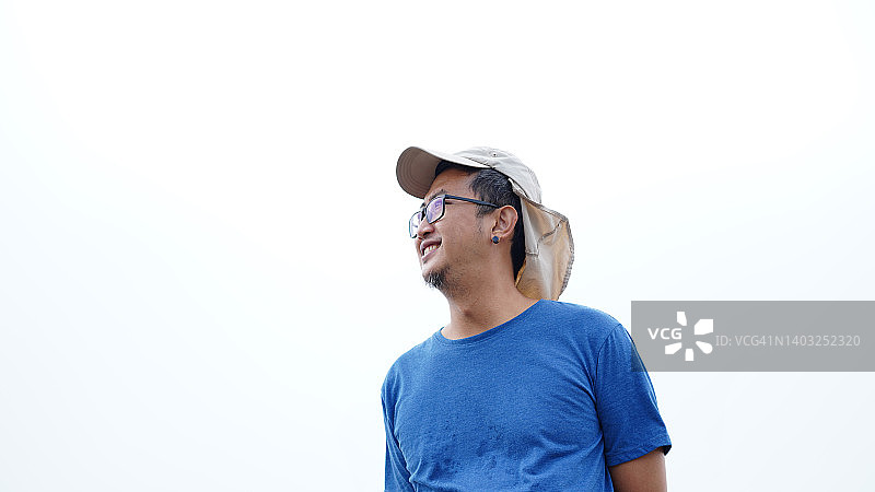 戴着帽子的亚洲中年男子肖像，站在户外，以天空为背景图片素材