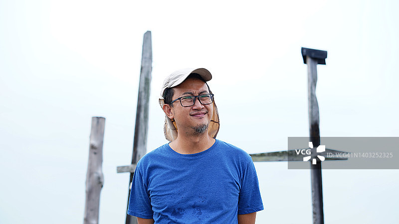 戴着帽子的亚洲中年男子肖像，站在户外，以天空为背景图片素材