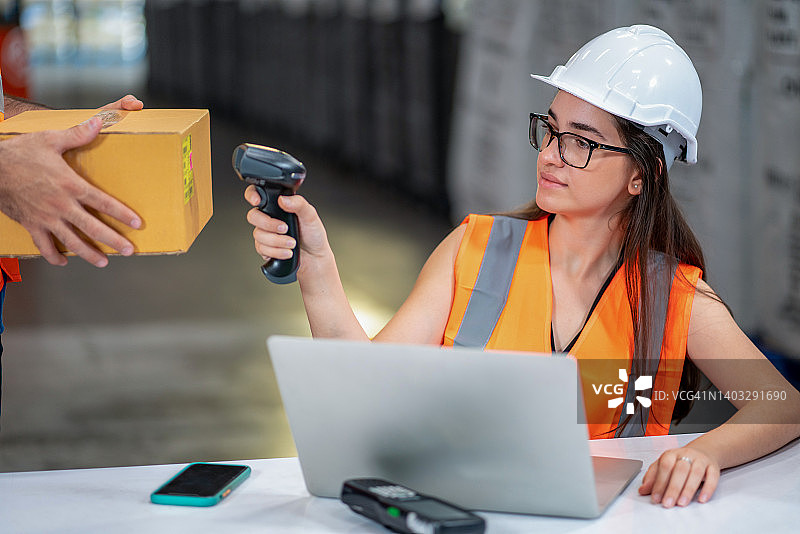 仓库里扫描箱子上条形码的女工人图片素材