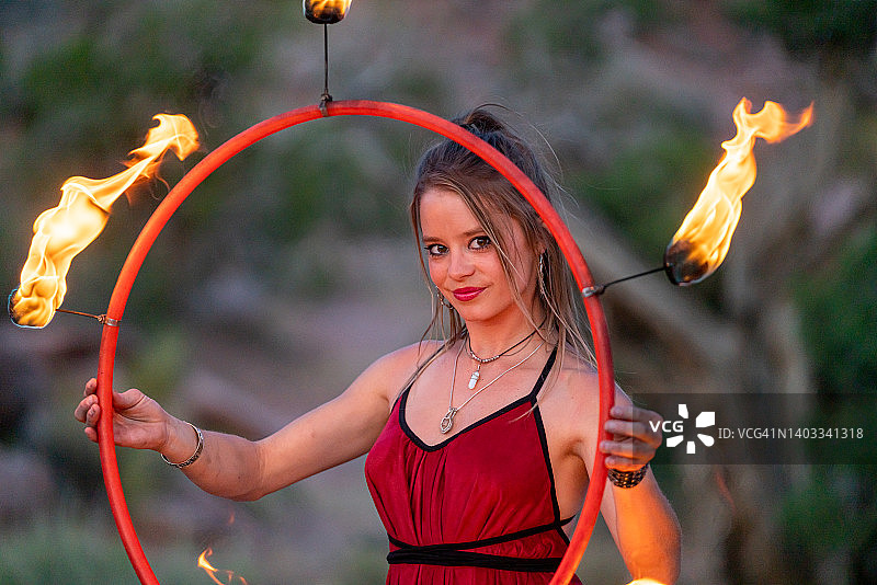 穿着红色服装的异域风情年轻火舞者，旋转着火圈图片素材