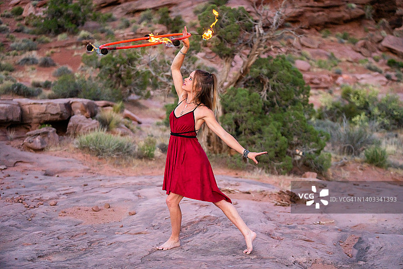 穿着红色服装的异域风情年轻火舞者，旋转着火圈图片素材