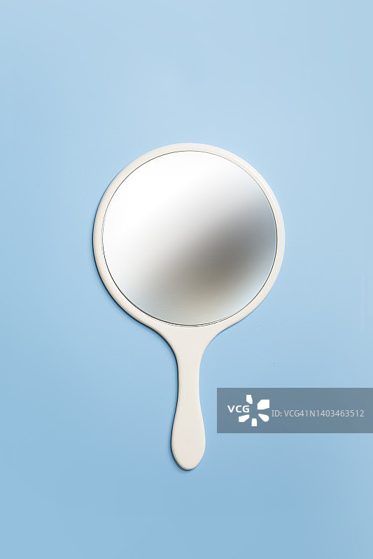 蓝色背景上的手持镜子图片素材