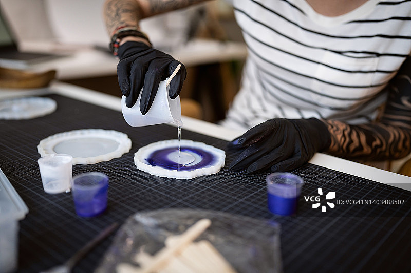 在家工作坊中将环氧树脂倒入硅胶模具的工艺女人图片素材