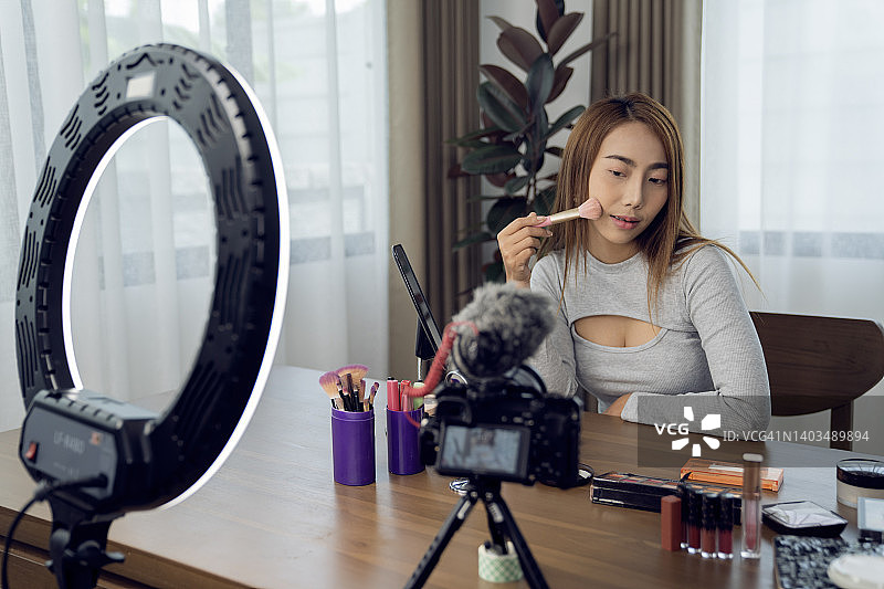 在家直播美妆产品的快乐年轻女子图片素材