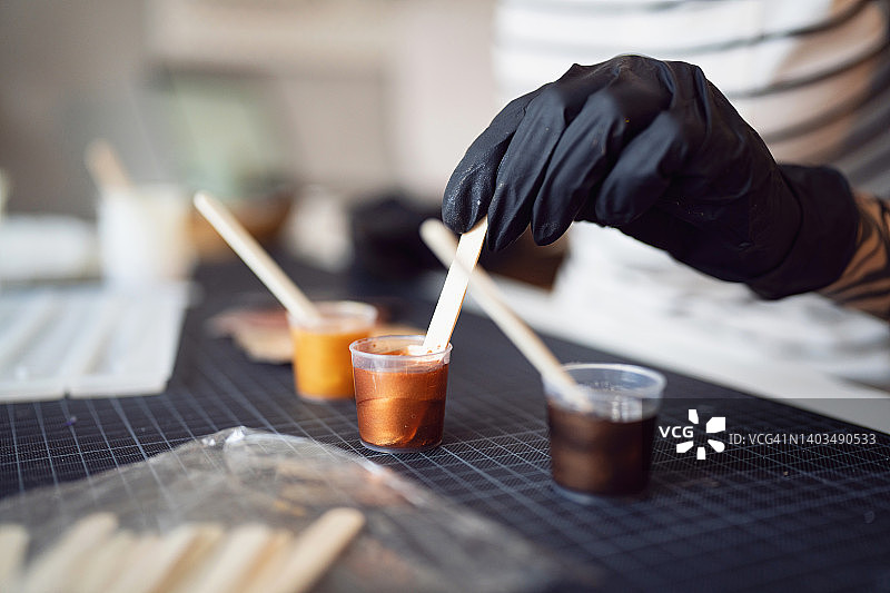 工艺女人用木棍在杯子里混合环氧树脂和闪光粉特写图片素材