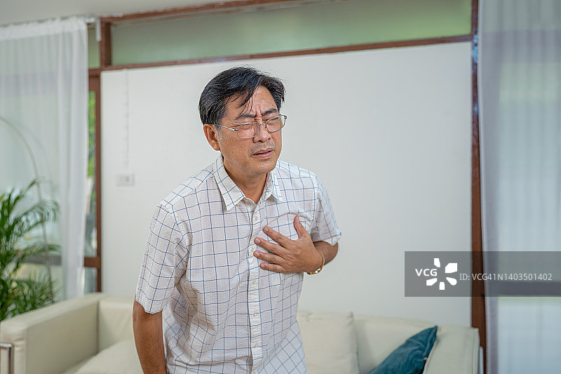感到不适并痛苦地捂住胸口的老年男人图片素材