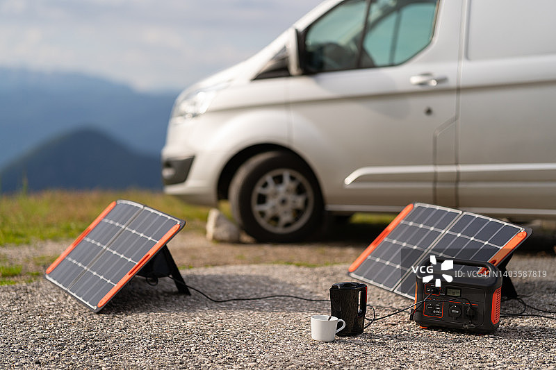 露营度假期间，可移动太阳能电池板为户外水壶充电图片素材