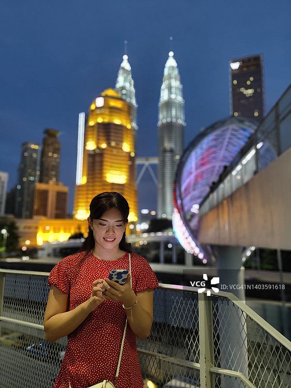 在城市景观上发短信的年轻亚洲女性图片素材