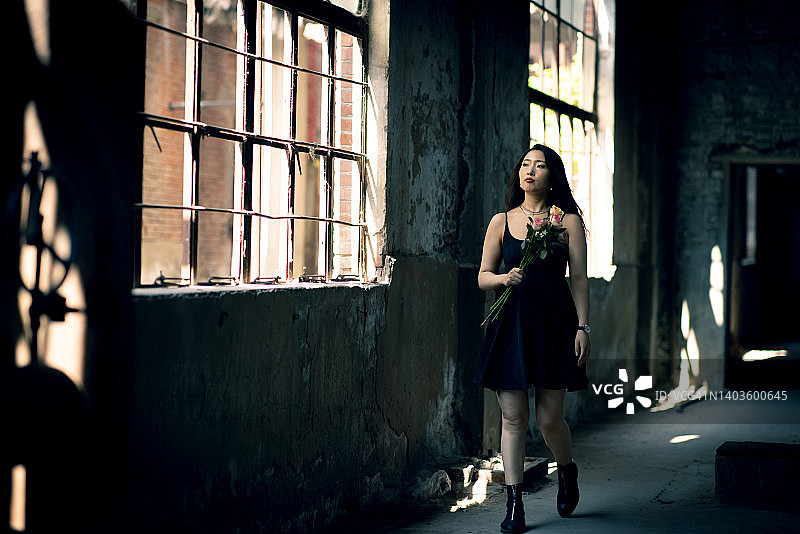 妇女手持玫瑰站在废墟中图片素材