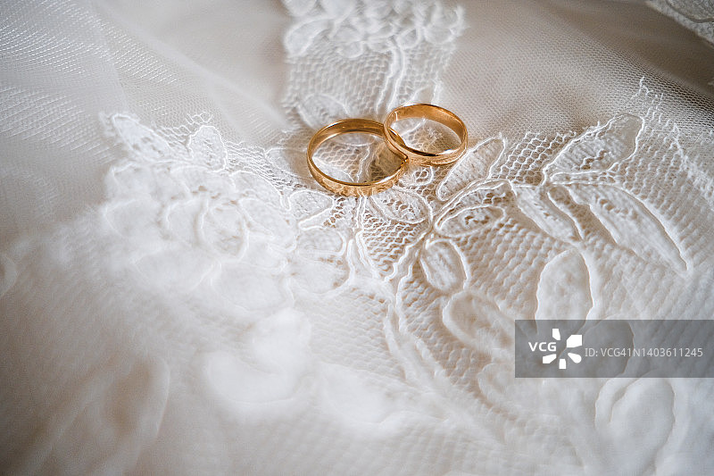 新娘面纱上的金色结婚戒指，精美镂空连衣裙上的珠宝，婚礼，忠诚与爱的象征图片素材