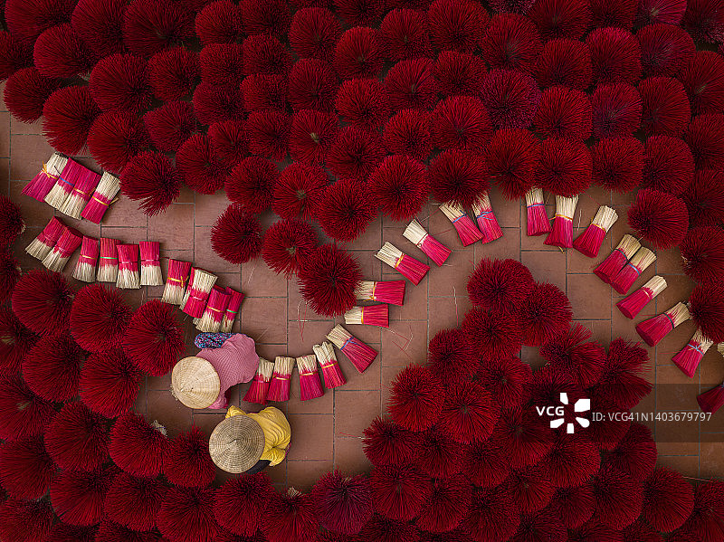 戴着斗笠的越南妇女在院子里晾晒香。越南河内香村准备在农历新年庆祝活动中出售的香。图片素材