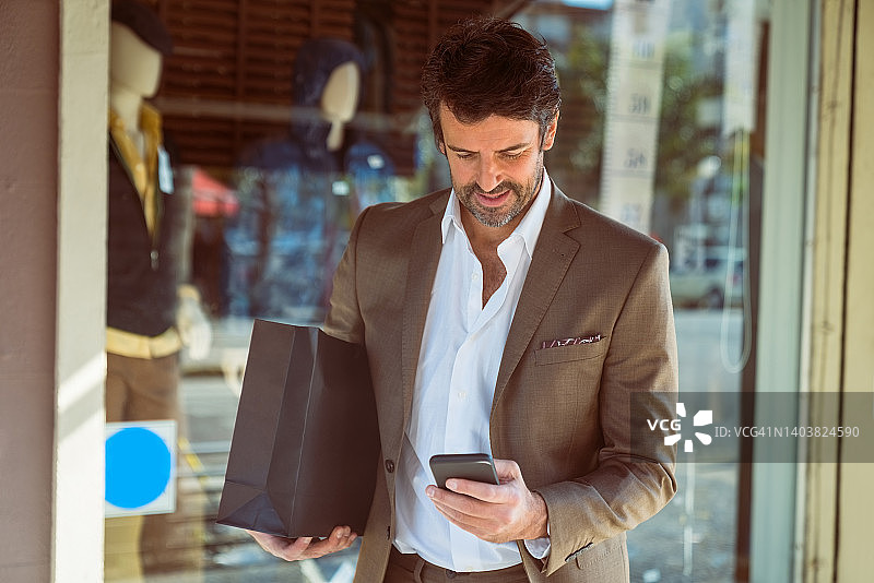 使用手机的购物袋商人图片素材