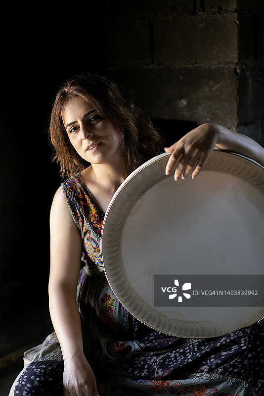 在阳光下演奏传统乐器erbane的年轻女人，黑色背景图片素材
