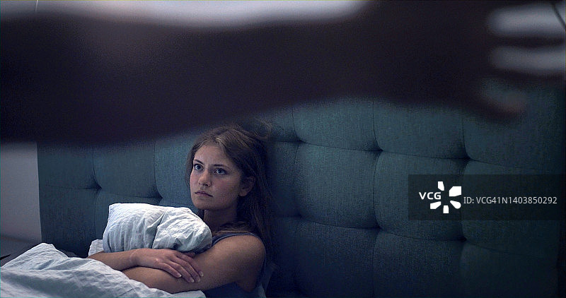 在床上看着抬起手臂的女人图片素材