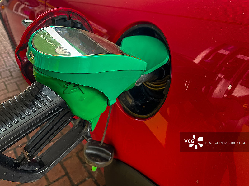 在加油站用汽油给汽车加油。燃料成本飙升，难以维持每周预算。建议减少出行以降低成本和账单图片素材