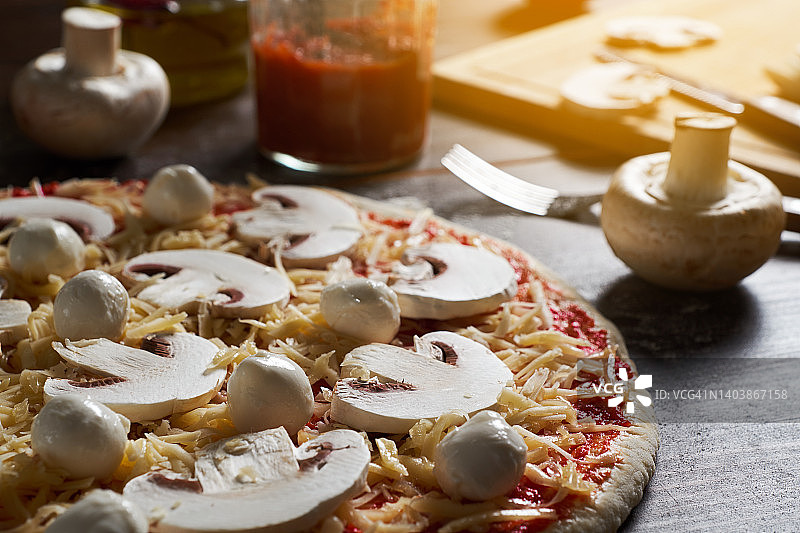 在家烹饪意大利蔬菜蘑菇披萨，披萨店，面包店或咖啡馆。一位女面包师、糕点师或厨师正在加入切碎的蘑菇。食物概念。逐步说明，自己动手。步骤1。图片素材