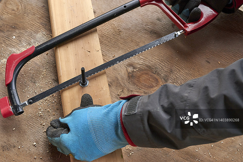 用锯子切割螺栓的中年男人图片素材