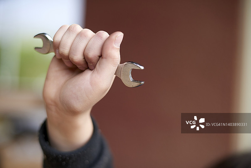 学龄男孩用拳头举起轮胎扳手图片素材