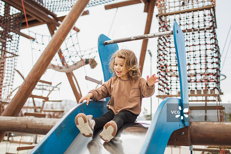 在儿童滑梯上玩耍的可爱快乐的女婴，儿童乐园和快乐童年瞬间图片素材