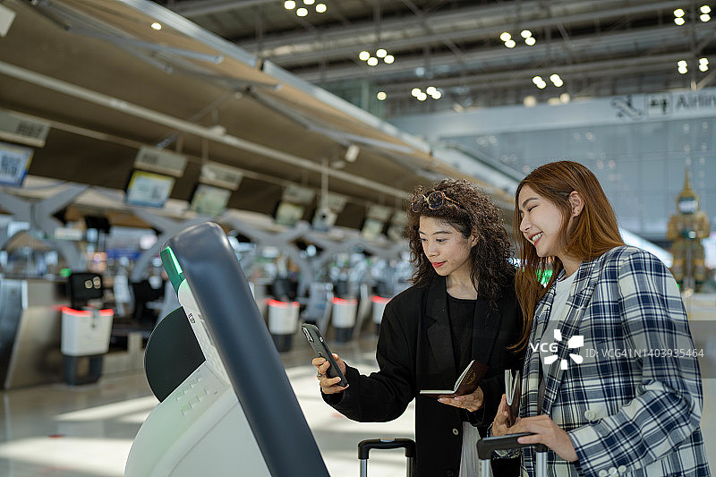 两位年轻的亚洲商务女性在机场自助办理登机手续图片素材