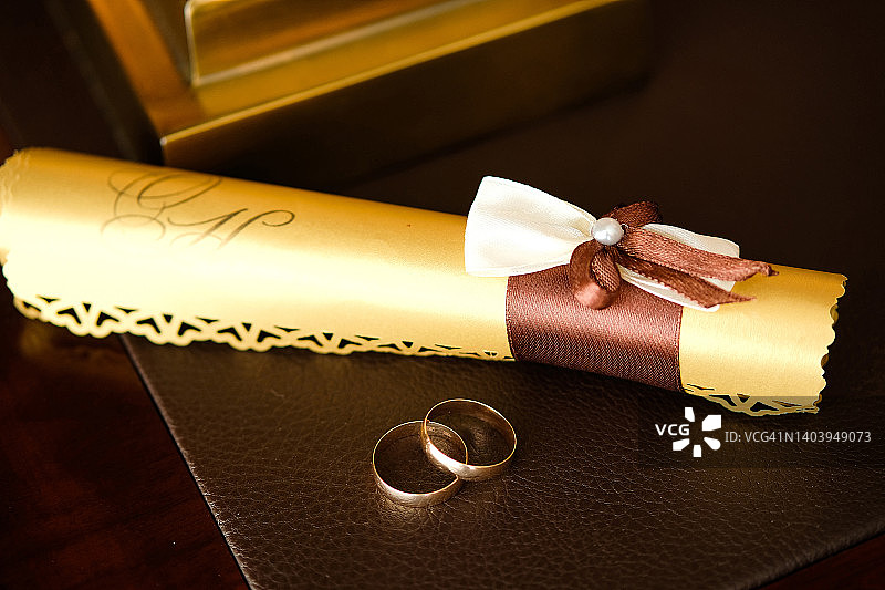 木质桌面上的金色婚戒与请柬图片素材
