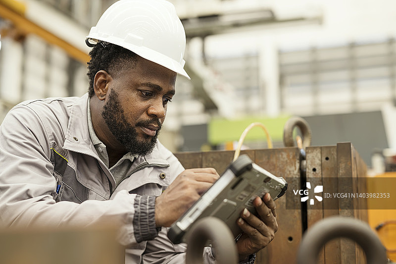 制造业中数据驱动的预测性维护：维护工程师在模具存储区使用平板电脑，按周期检查，确保在生产周期中定期监控和维护工具图片素材