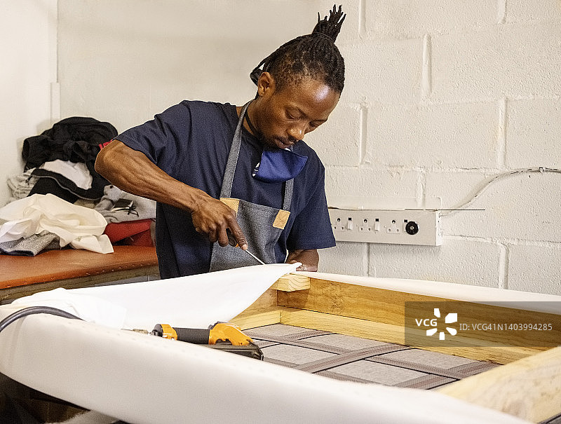 室内装潢工人在车间里修理木框上的织物图片素材