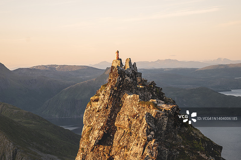 女人坐在挪威塞尼亚岛的岩石顶峰上图片素材