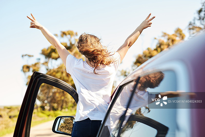 公路旅行，女人车旁比划和平手势图片素材