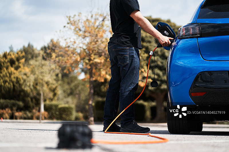 身份不明的男人给电动汽车充电图片素材