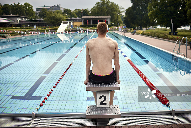 游泳运动员坐在室外公共游泳池的起跳台上图片素材