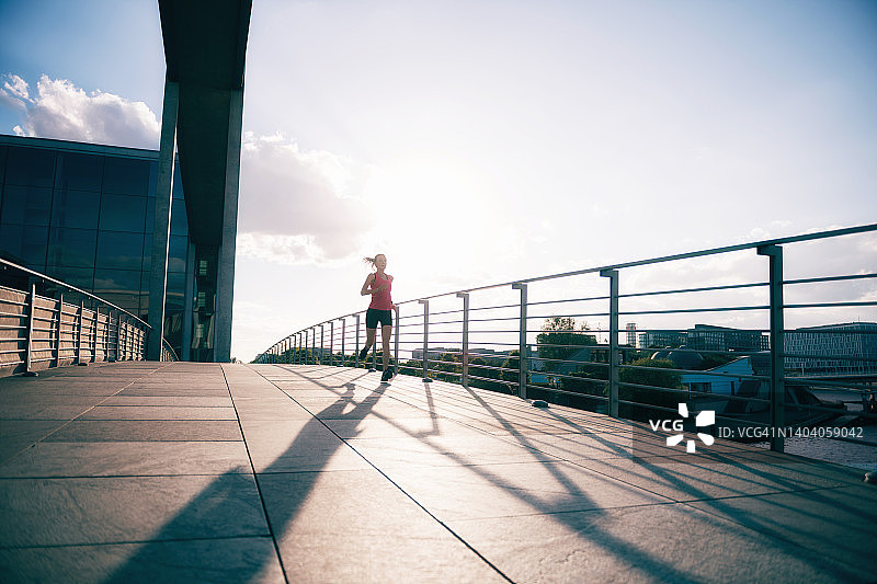 日落时分，在桥上奔跑的年轻女子图片素材