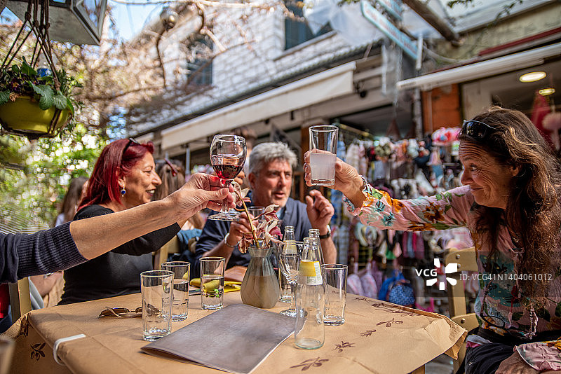 在希腊海岸享受当地饮品庆祝的中年朋友图片素材