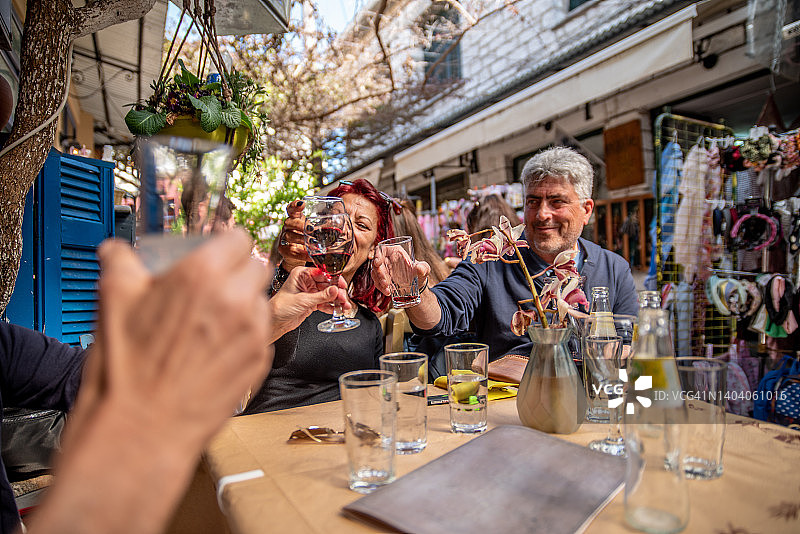 在希腊街头小酒吧里举杯庆祝的中年朋友图片素材