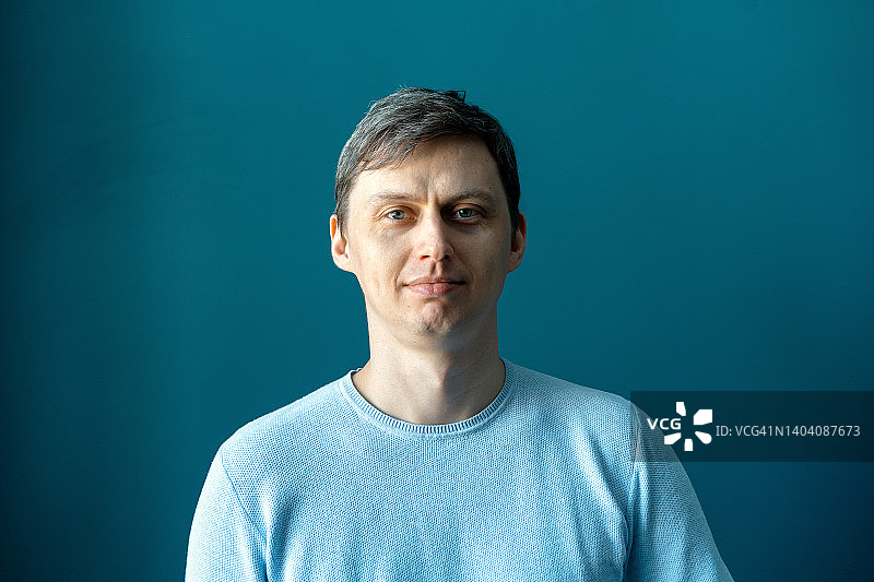 靠在蓝色墙壁上的中年男人图片素材