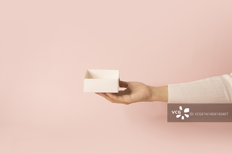 手持粉色背景上的空盒子图片素材