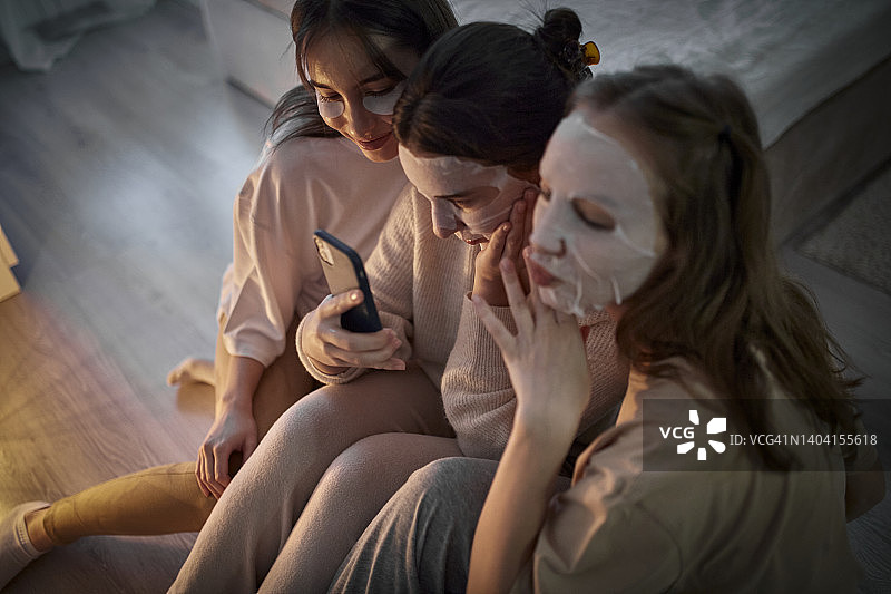 三个敷面膜玩手机的女人图片素材