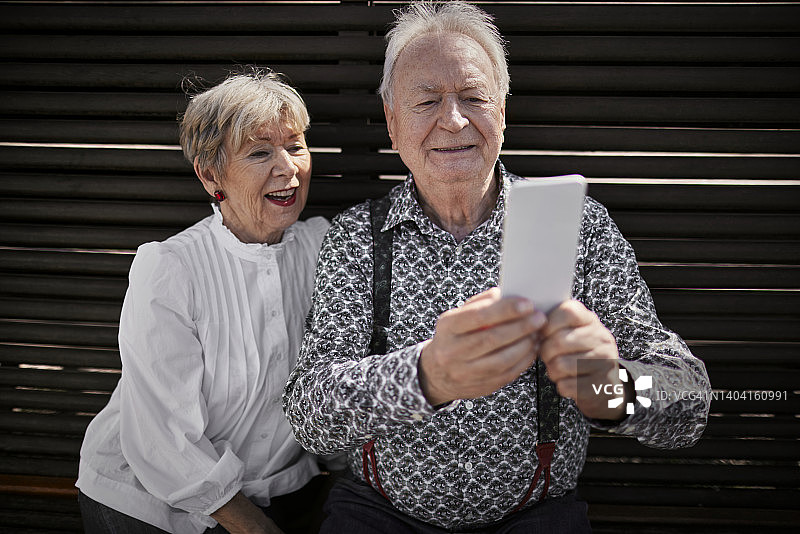 在长椅上使用手机的老年夫妇图片素材