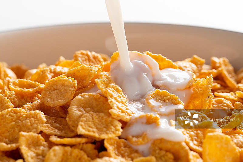 陶瓷盘中的干蜂蜜玉米片，可搭配有机农场蔬菜大豆、杏仁或动物奶。顶视图，复制空间。健康饮食、素食和纯素早餐概念图片素材