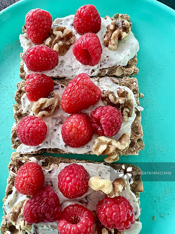 燕麦、葵花籽脆面包，上面覆盖着奶油奶酪、覆盆子和核桃图片素材