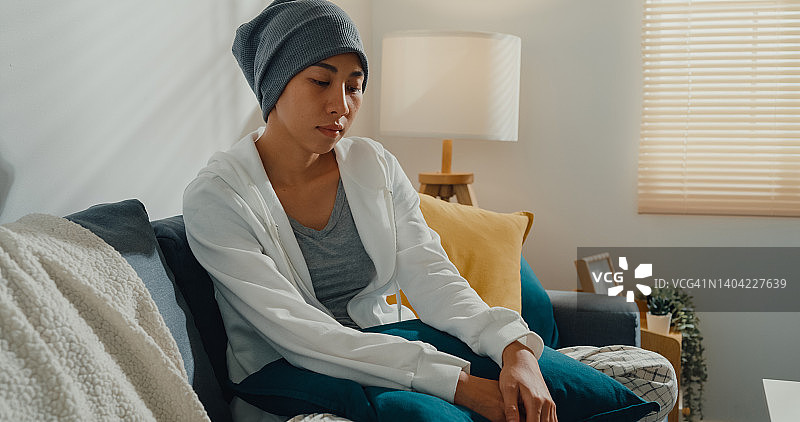 坐在客厅沙发上，患有癌症的沮丧的年轻亚洲女性图片素材