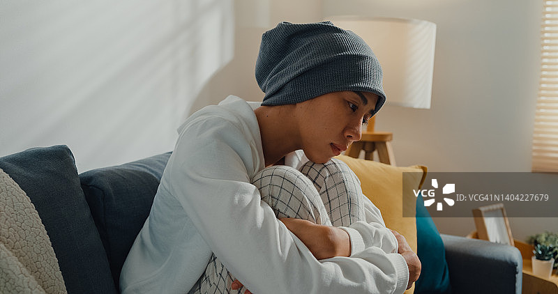 坐在客厅沙发上，患有癌症的沮丧的年轻亚洲女性图片素材