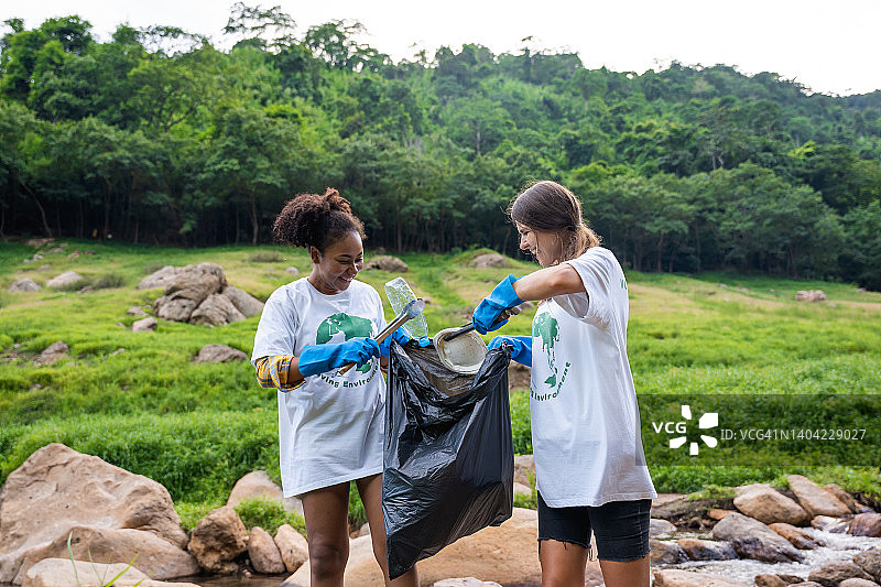 联合起来作为自然保护志愿者在山上捡垃圾的多民族年轻女性图片素材