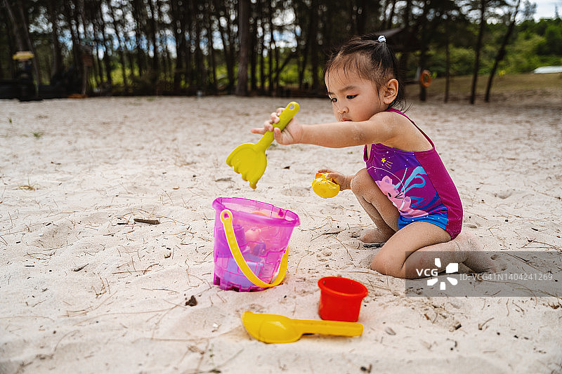 在沙滩上玩沙子的小女孩图片素材