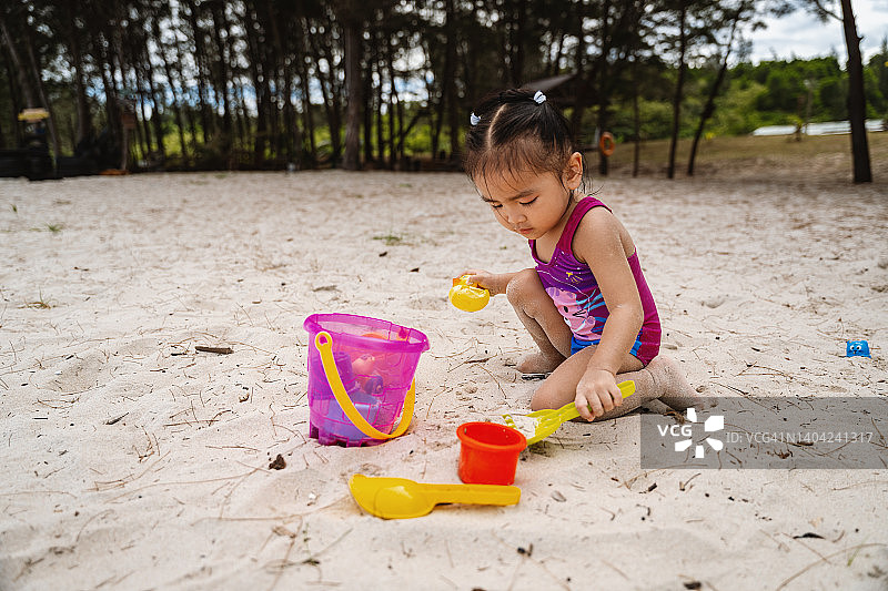 在沙滩上玩沙子的小女孩图片素材