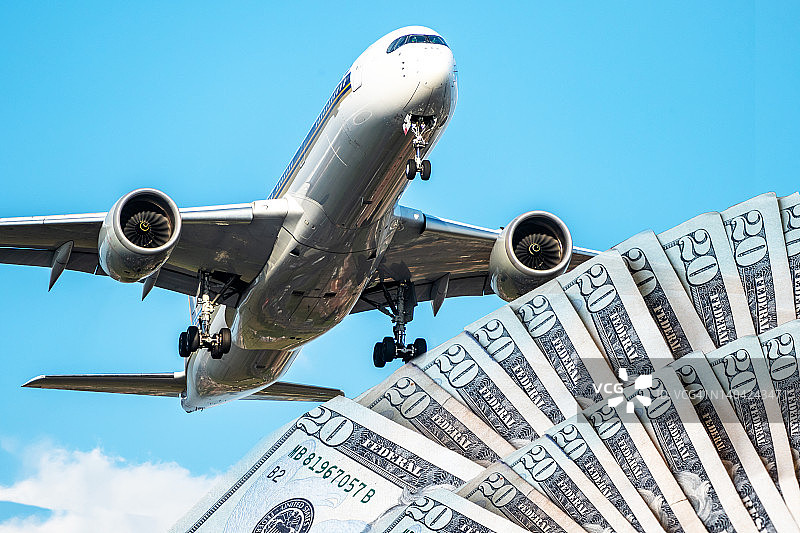 飞行中的飞机与美元：航空业运营成本上涨图片素材